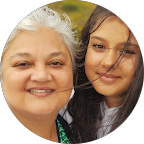Woman with white hair smiling next to a younger person with long brown hair, both outdoors.