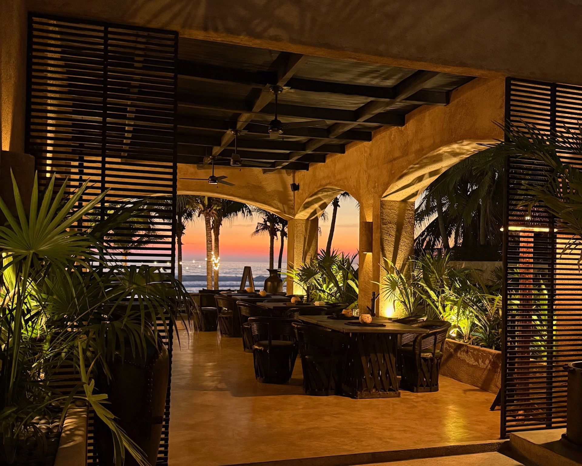 A restaurant with tables and chairs and a sunset in the background