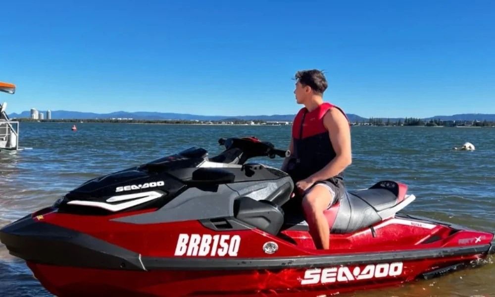 A man is sitting on a red jet ski in the water.