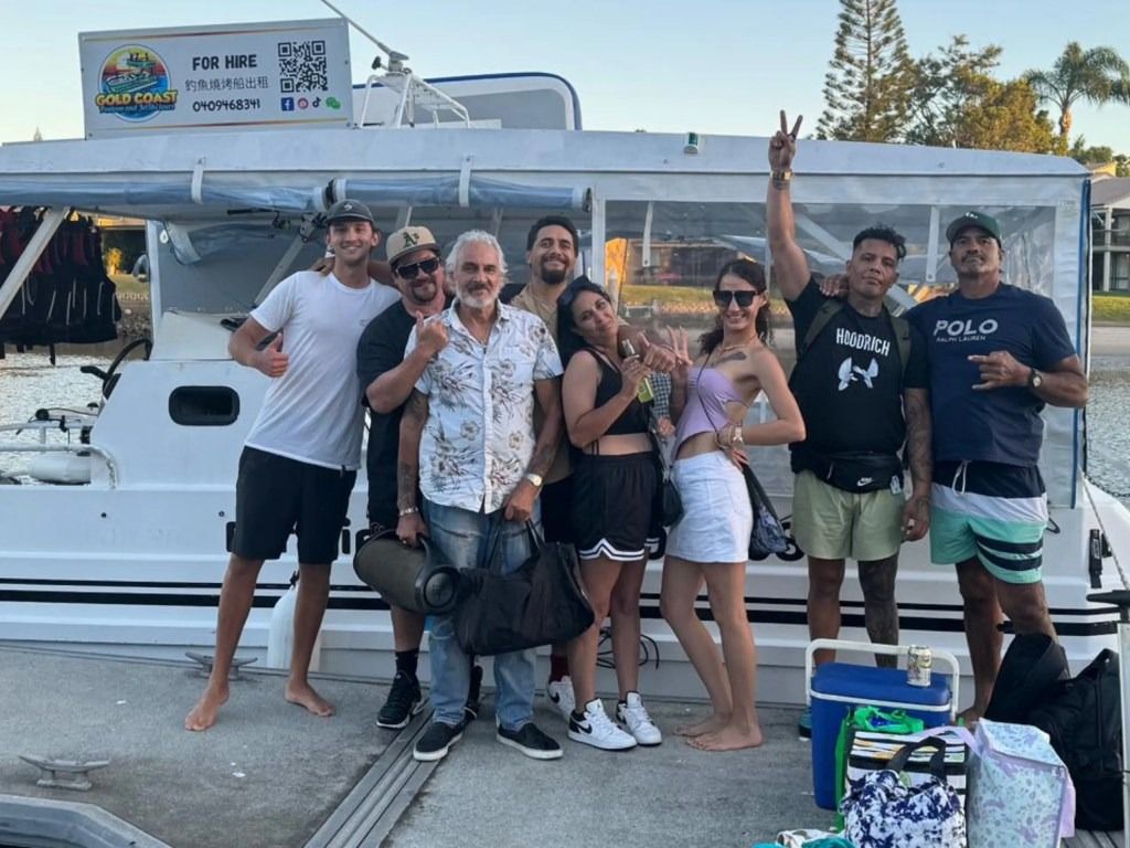 A group of people are posing for a picture in front of a boat.