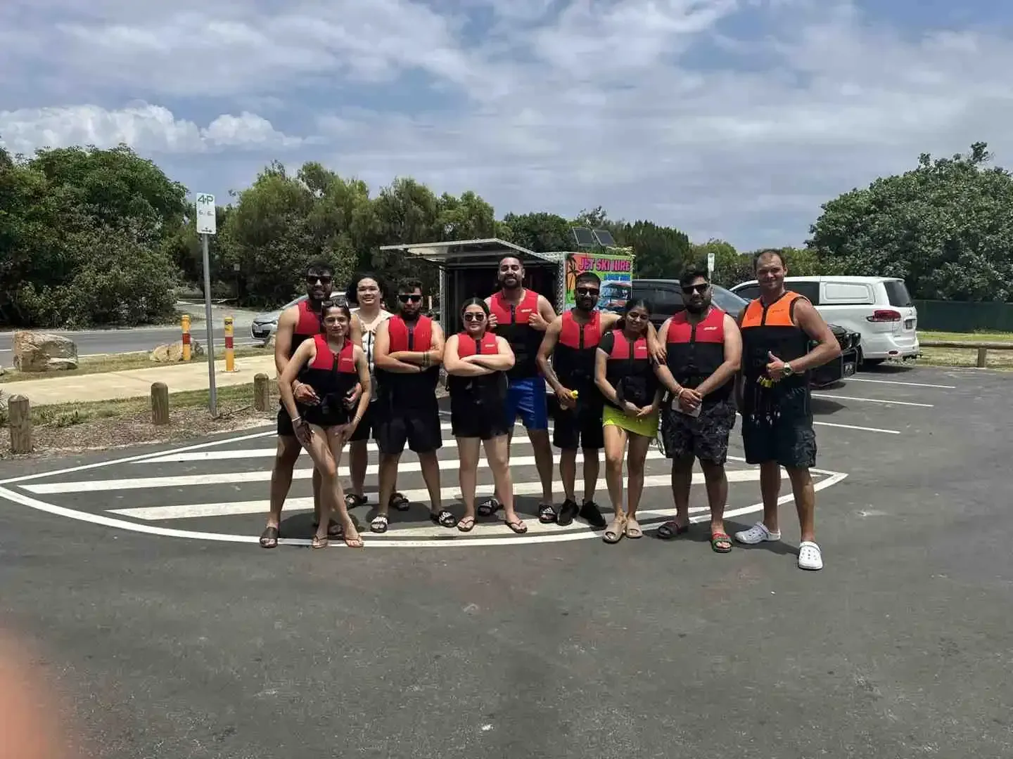 A happy group of nine people wearing life jackets and ready for a jet ski or pontoon tour adventure on a sunny day - First time jet ski
