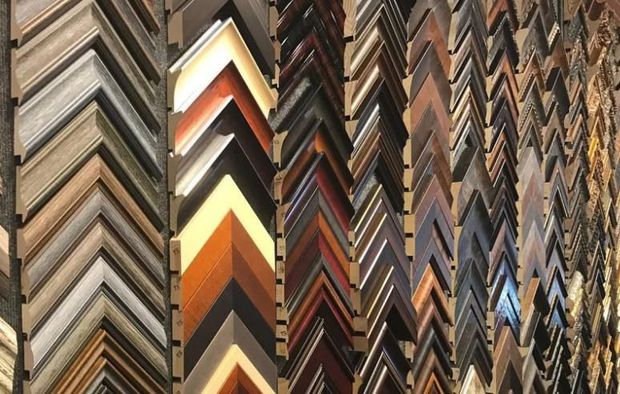 Rows of colorful, patterned picture frame moldings displayed vertically in a shop wall