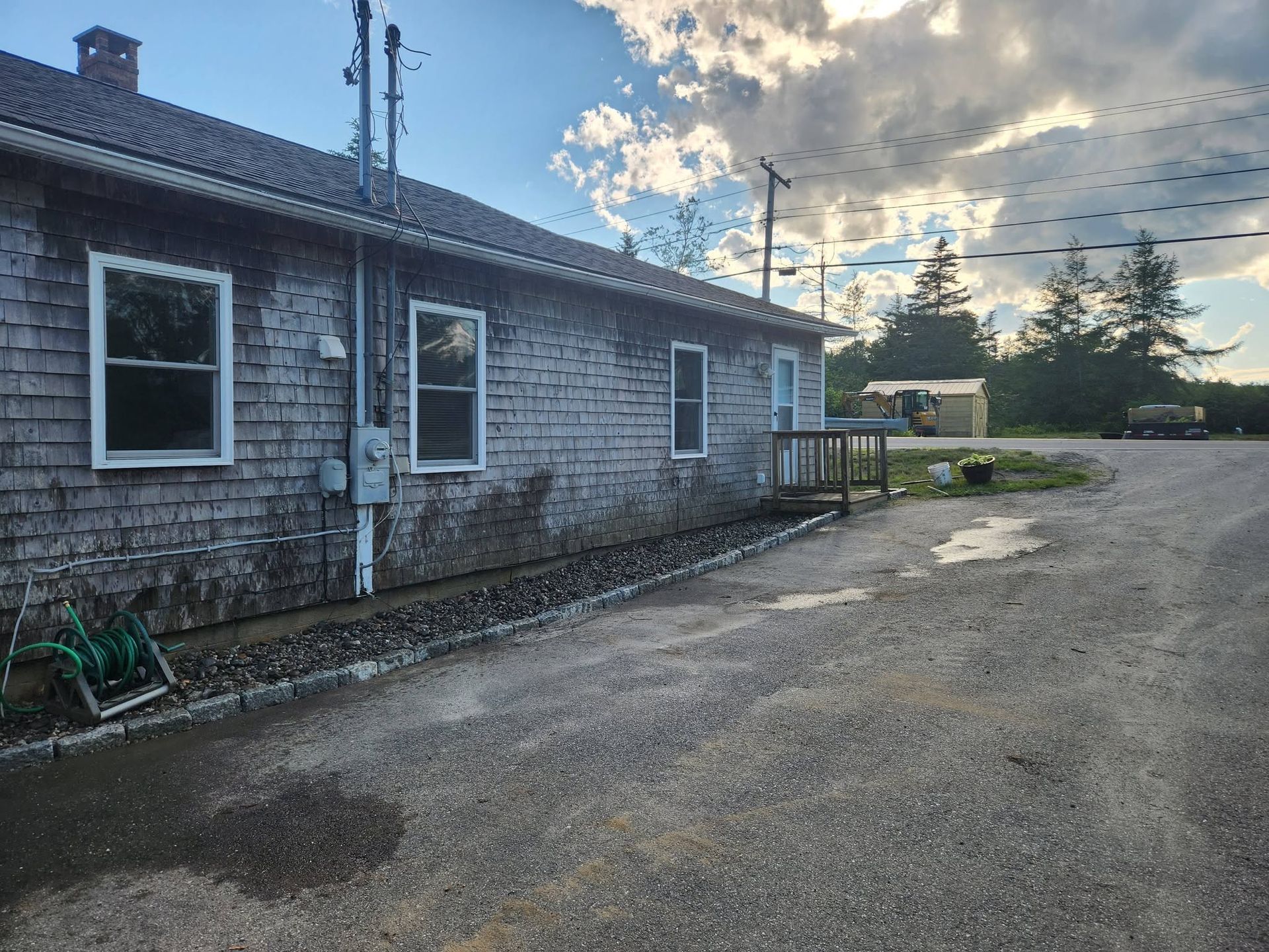 Weathered blue-gray building beside a gravel lot under a cloudy evening sky