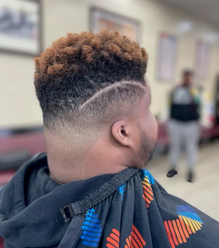 A person with a short, textured top and a clean skin fade haircut, featuring a vertical script tattoo on their neck.