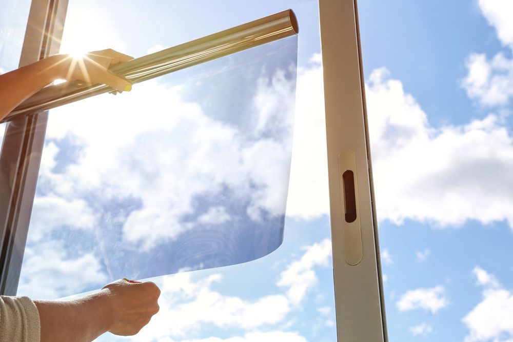 A Person Is Applying Solar Film To A Window — Jay's Tint in Smithfield, QLD