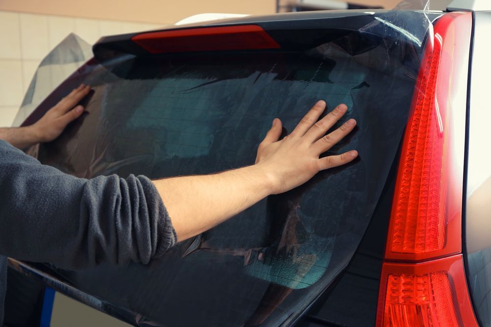A Person Is Applying Tinted Window Film To The Back Window Of A Car — Jay's Tint in Smithfield, QLD