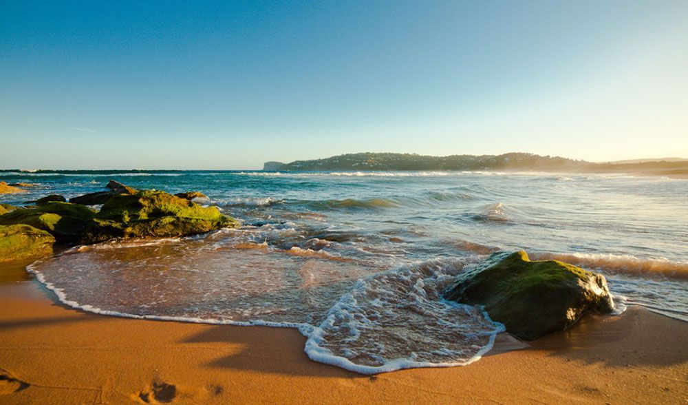 A Beach With Rocks In The Sand And Waves Crashing On The Shore — Jay's Tint in Northern Beaches, QLD