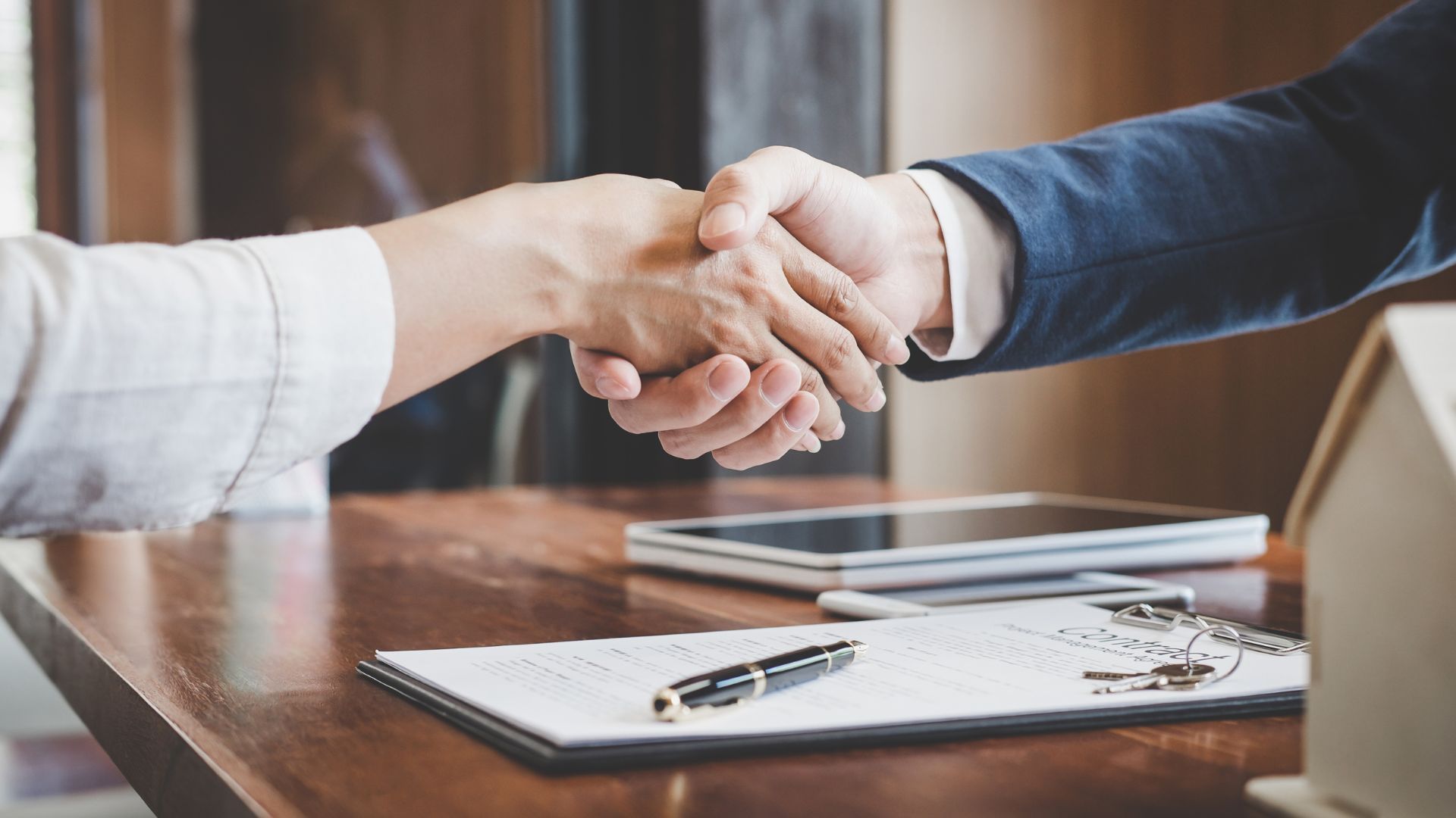 A man and a woman are shaking hands over a table.