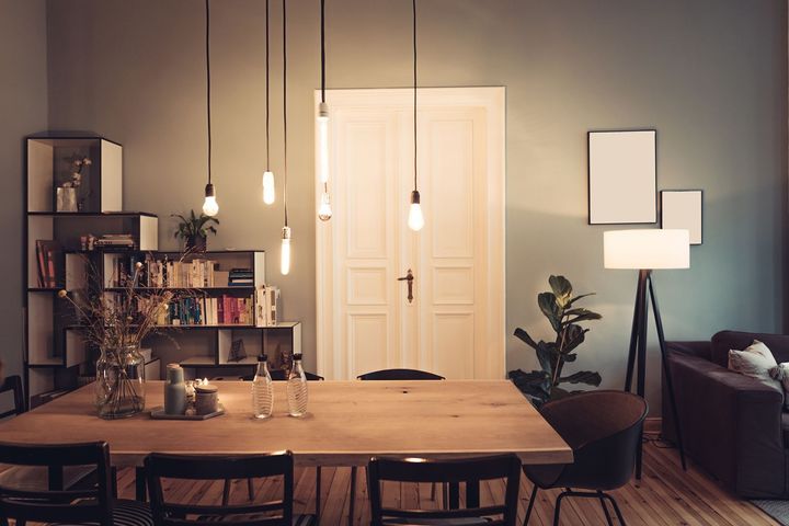 A living room with a dining table and chairs and a lamp.