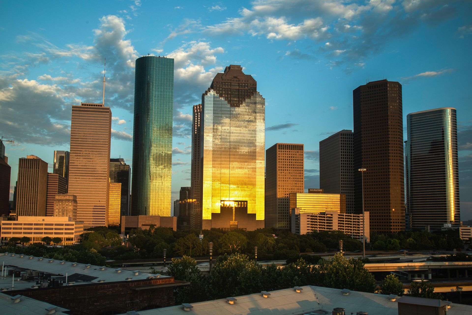 Downtown skyline at sunset with glass skyscrapers reflecting golden light under a blue sky