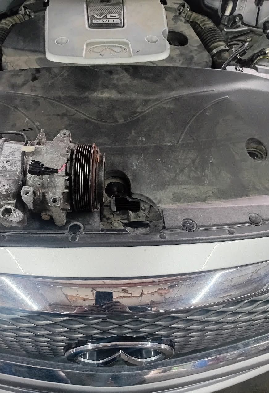 Open car hood with exposed engine and front grille visible in a garage-like setting