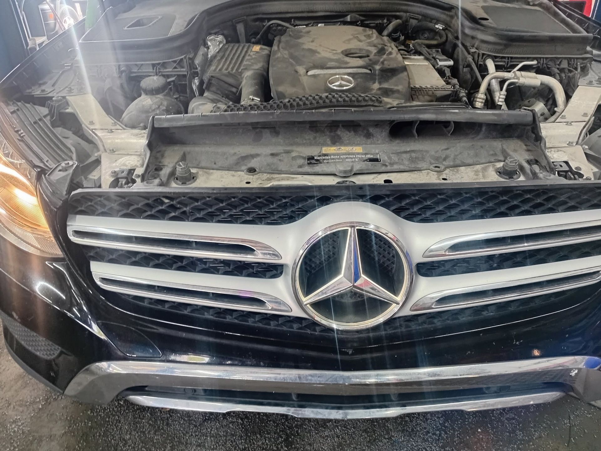 Front view of a black Mercedes-Benz with the hood open, showing the engine bay.