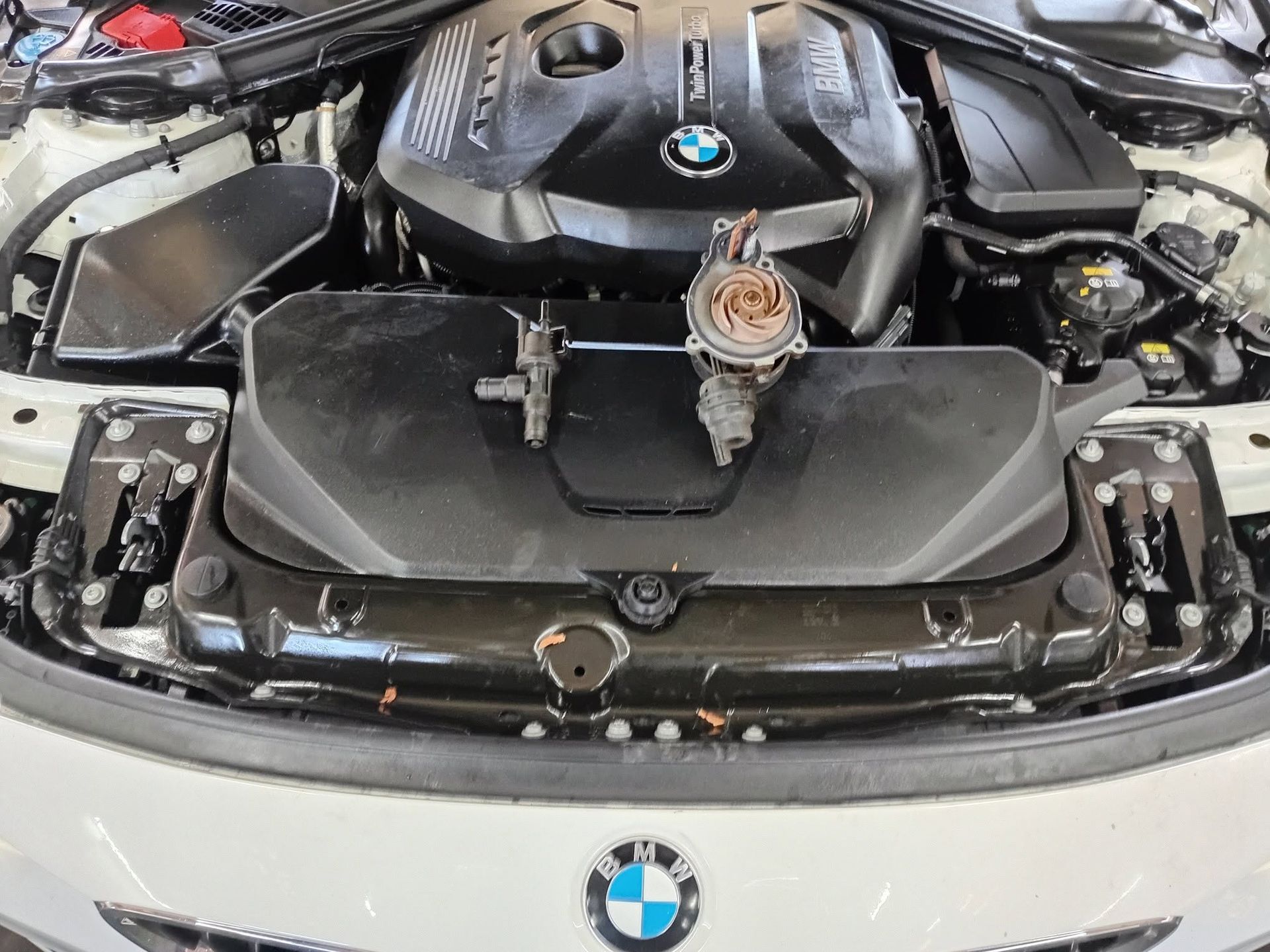 BMW engine bay with front body panels removed, exposing the car’s front structure and engine components.