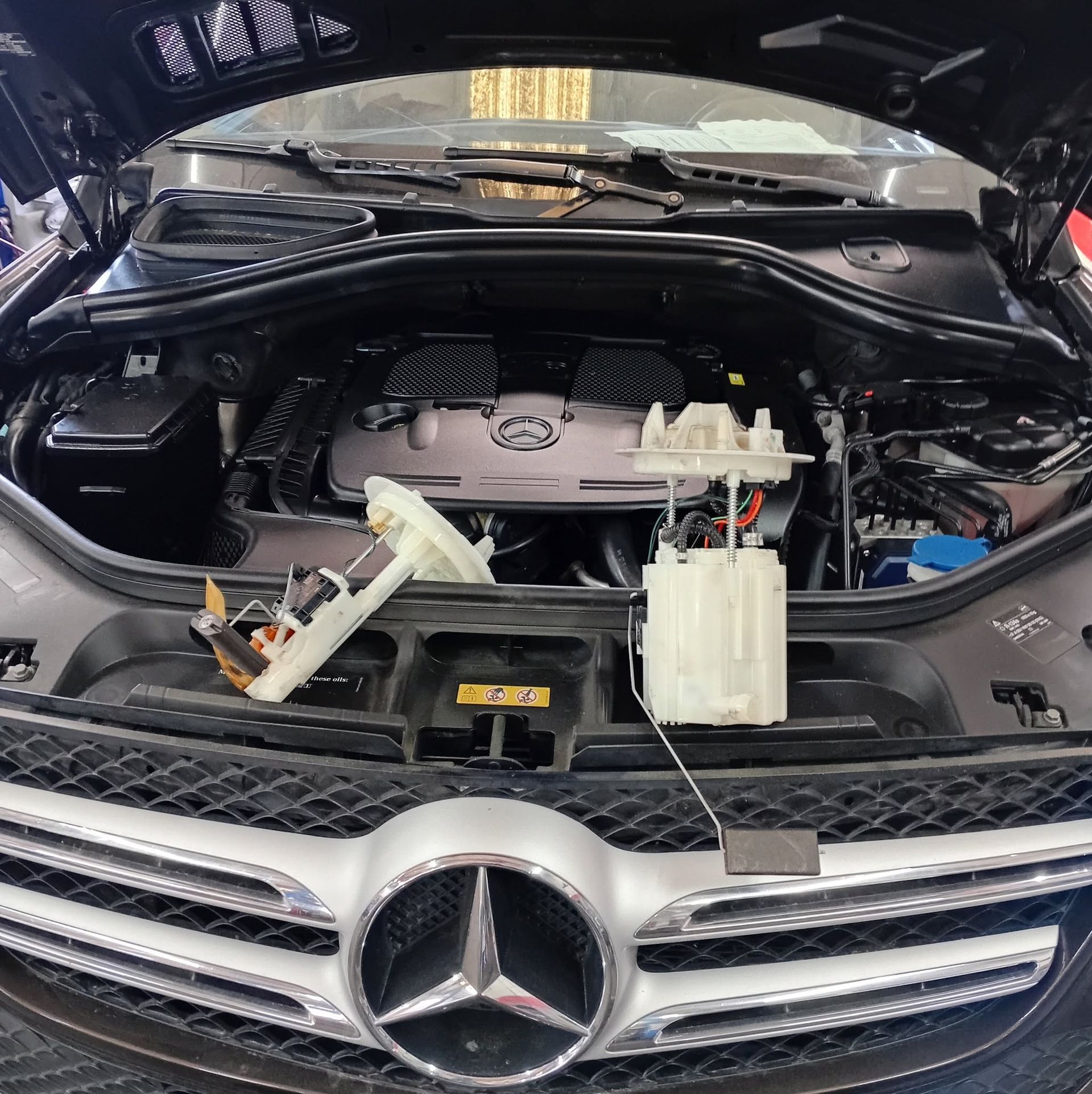Mercedes-Benz engine bay with dashboard panels and white plastic components removed and placed in front