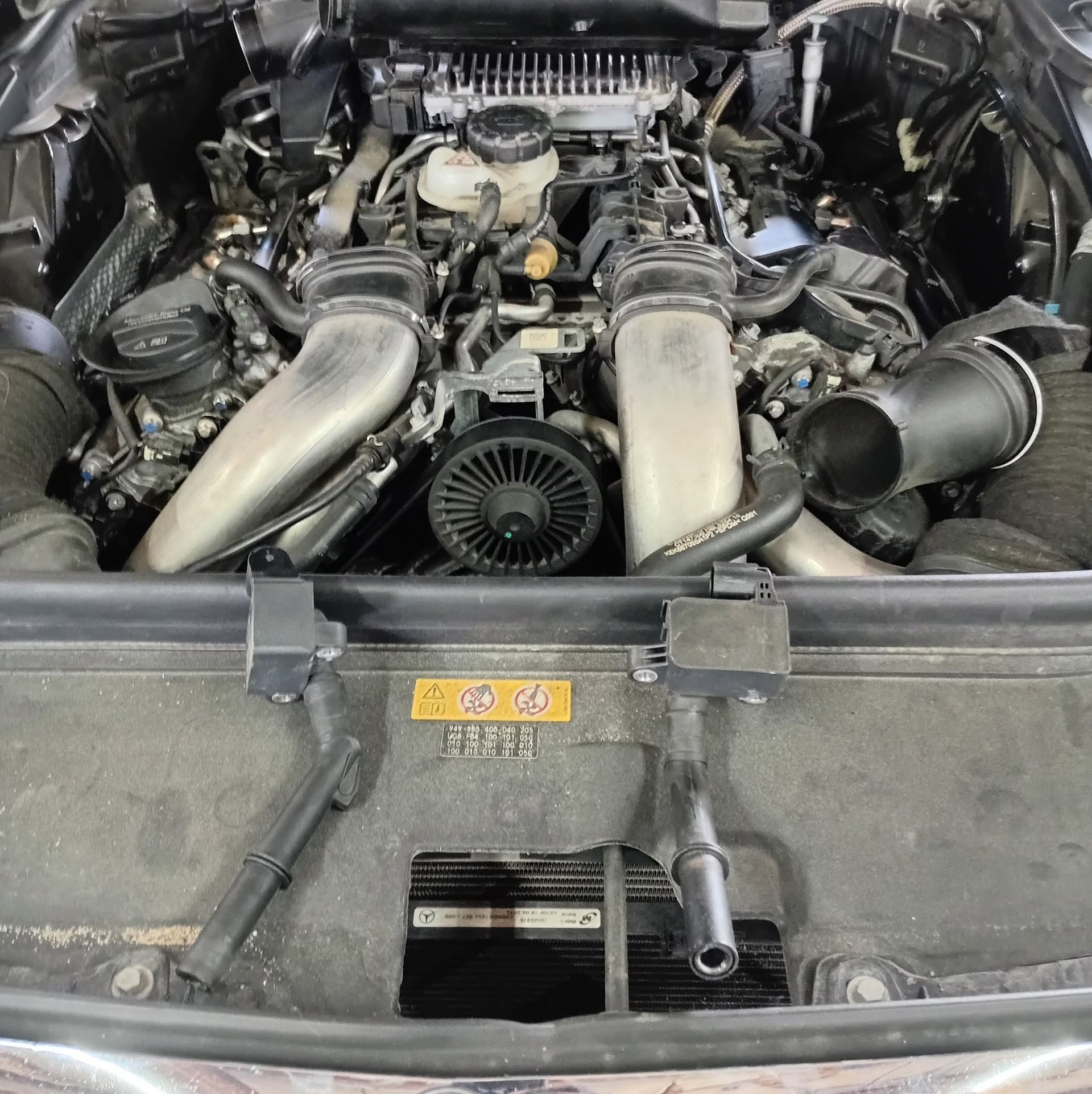 Close-up of a car engine bay with twin air intakes and visible mechanical components.