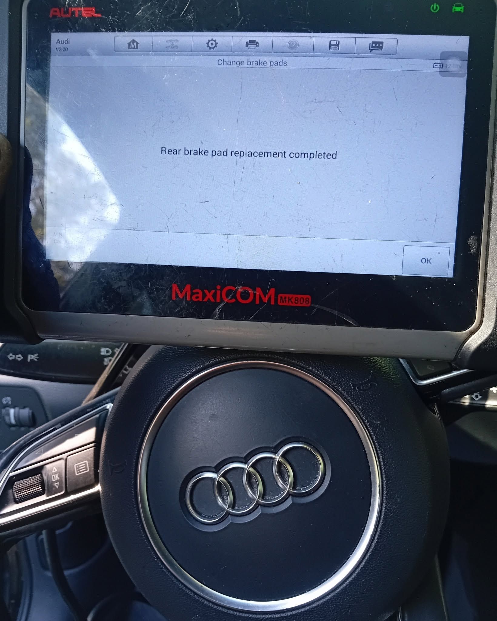 Audi steering wheel with an Autel MaxiCOM scanner displaying an error message on the screen.