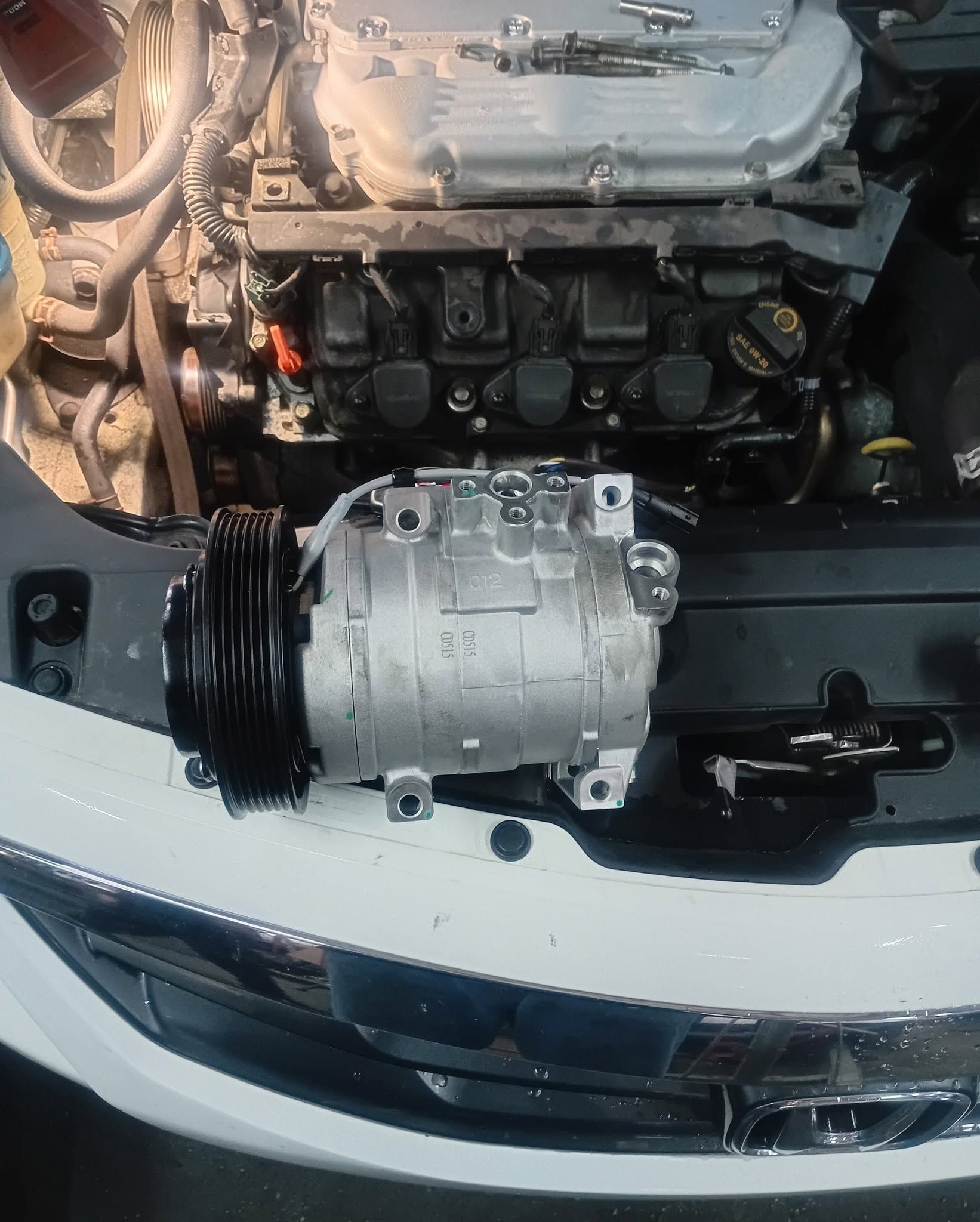 Close-up of a car engine bay with a silver component mounted above the front bumper.