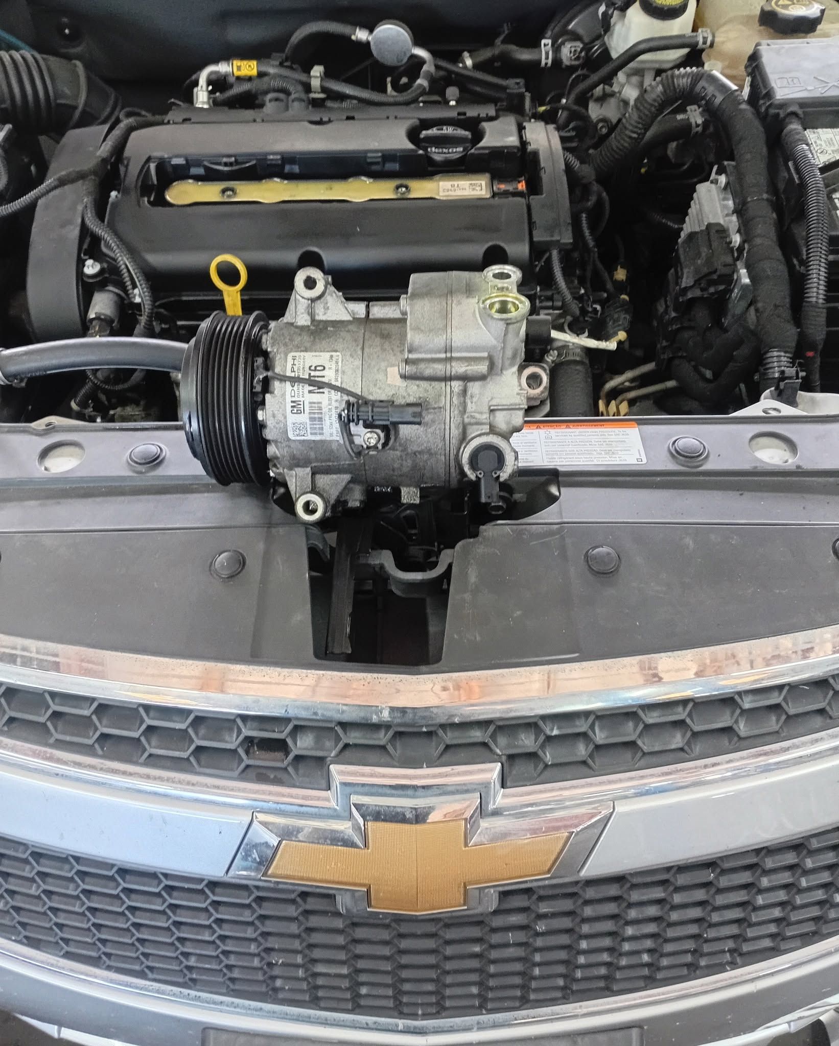 Engine bay of a Chevrolet with the front grille and emblem visible, showing exposed engine components.