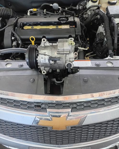 Engine bay of a Chevrolet with the front grille and emblem visible, showing exposed engine components.
