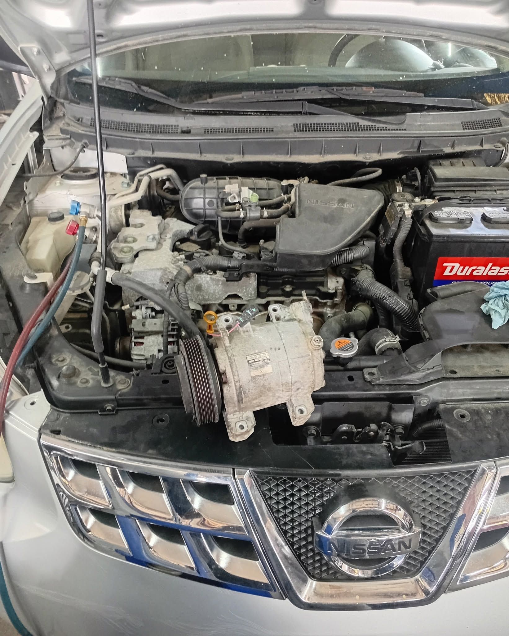 Open SUV hood showing engine bay with exposed components and front Nissan grille.