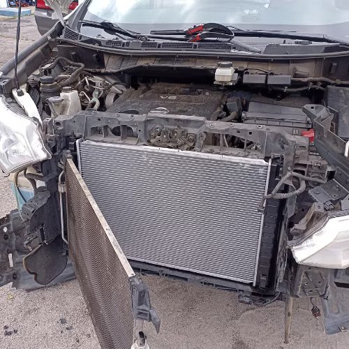 Front view of a severely damaged car with the bumper removed, exposing the radiator and engine bay.