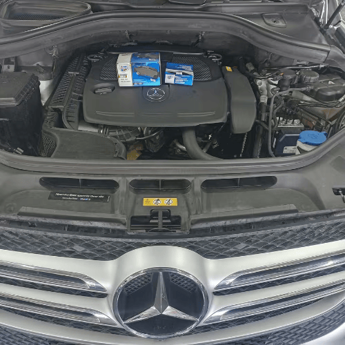 Open Mercedes engine bay with a protective cover and parts box on top