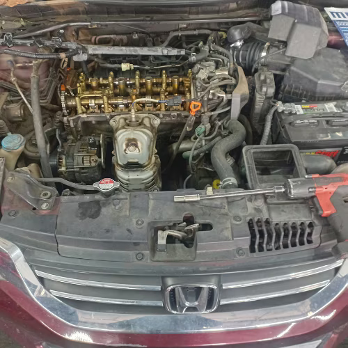 Honda car engine bay with hood open, showing exposed engine components and front grille.