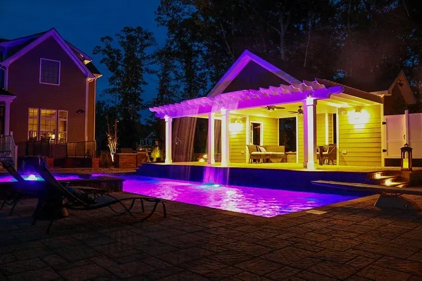 House and pool lit with vivid purple and yellow lights at night