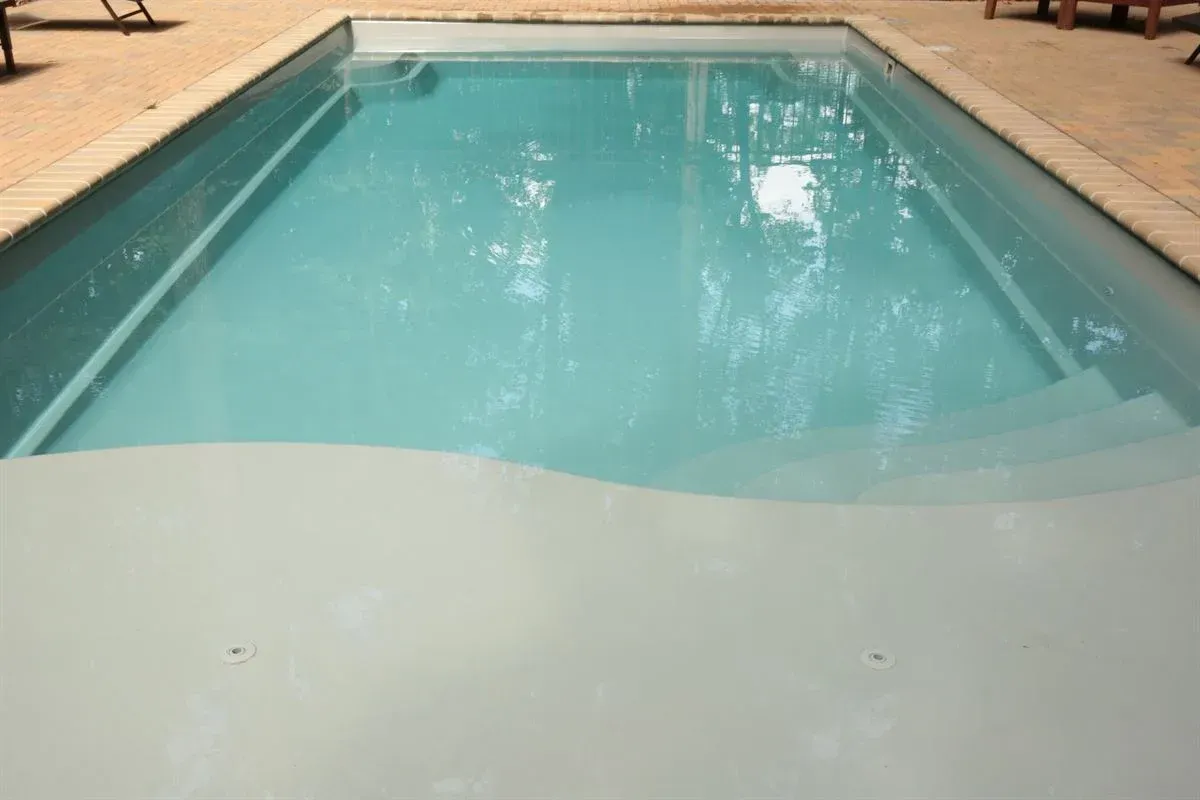 Rectangular outdoor swimming pool with turquoise water and beige pool deck