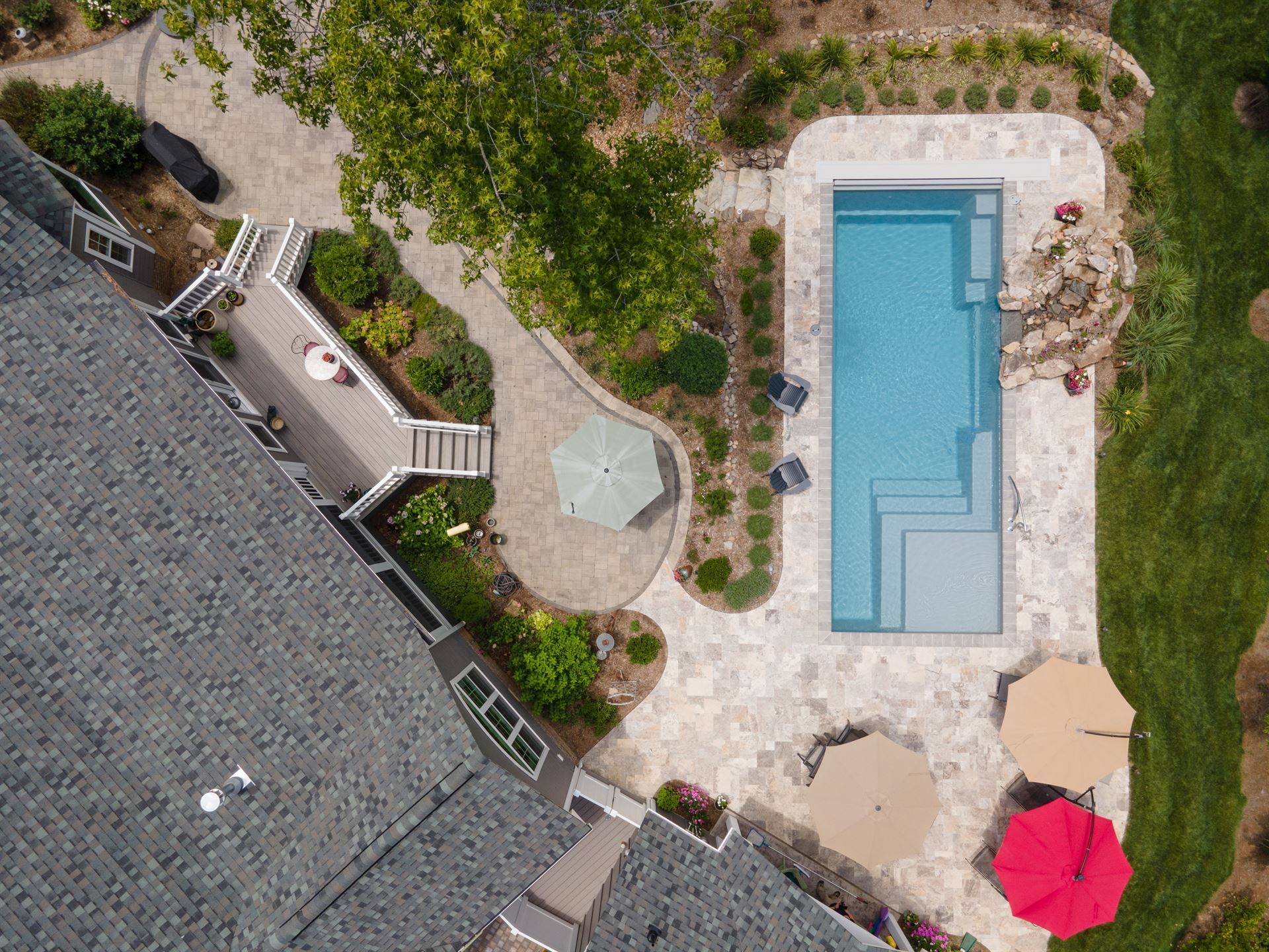 Aerial view of a backyard with a rectangular pool, patio furniture, and surrounding landscaping