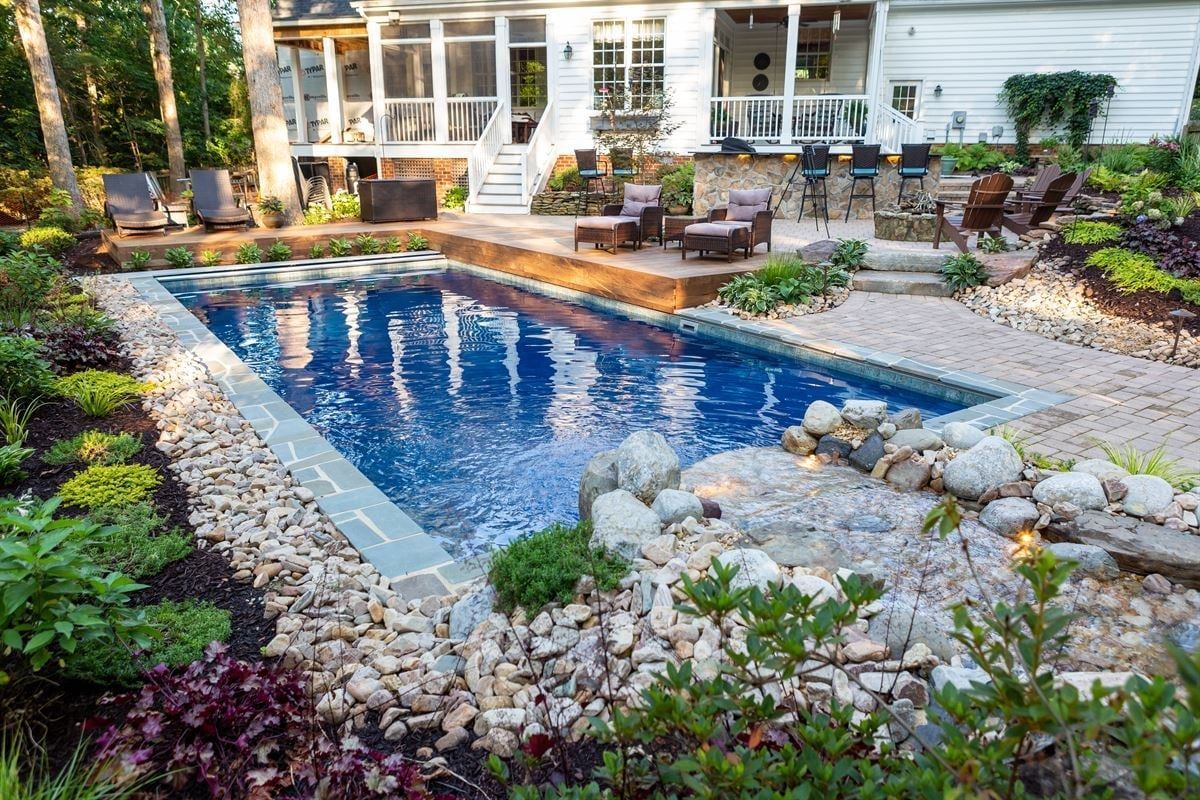 Backyard pool with stone landscaping and a patio outside a house
