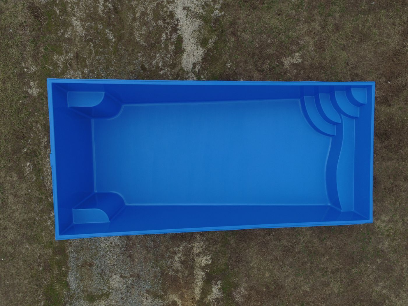 Blue rectangular plastic tray or mold on a rough gray surface.
