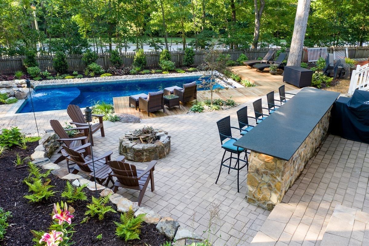 Backyard patio with pool, fire pit, lounge chairs, and stone bar seating