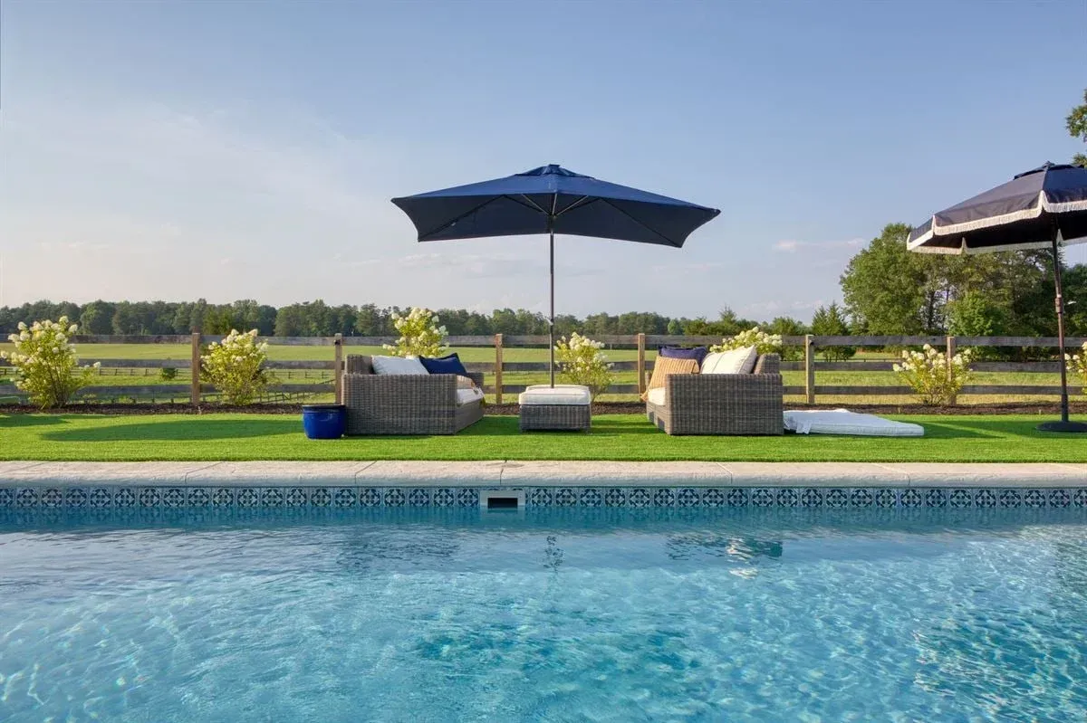 Poolside lounge chairs and umbrella beside a blue swimming pool on a sunny day