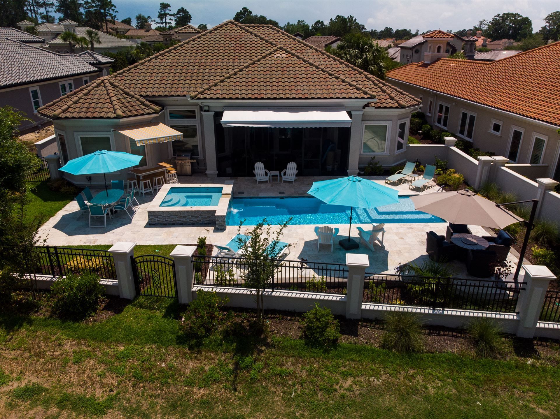 Modern home with a backyard pool, hot tub, and patio umbrellas under a tiled roof