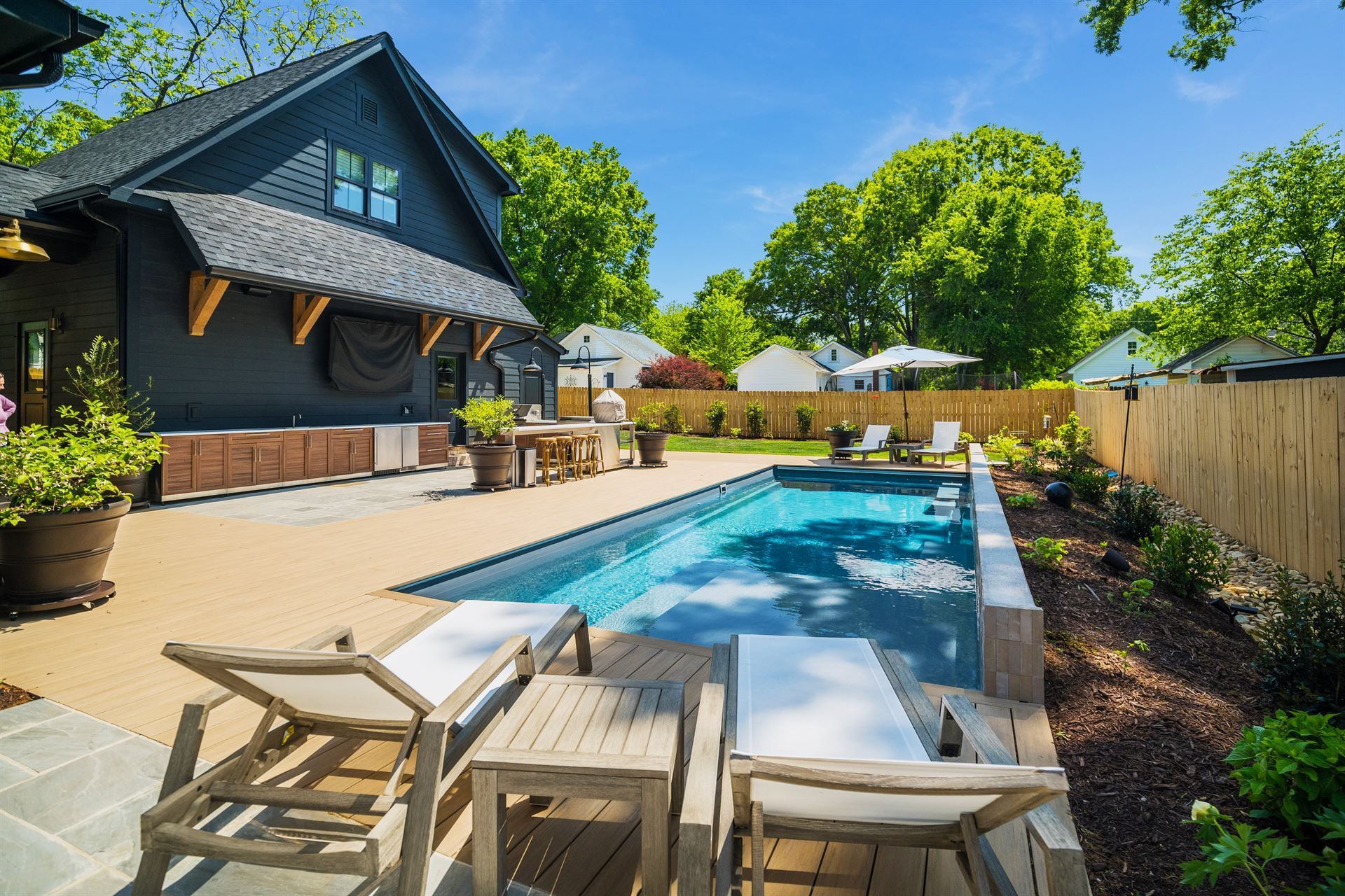 Backyard pool beside a patio and house, with lounge chairs and bright blue water