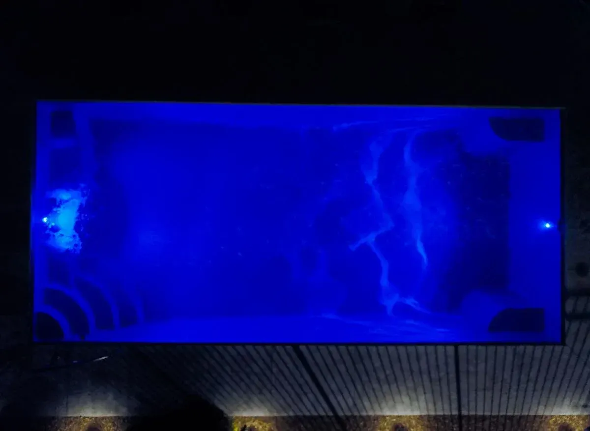 Blue-lit rectangular display glowing at night above a building facade