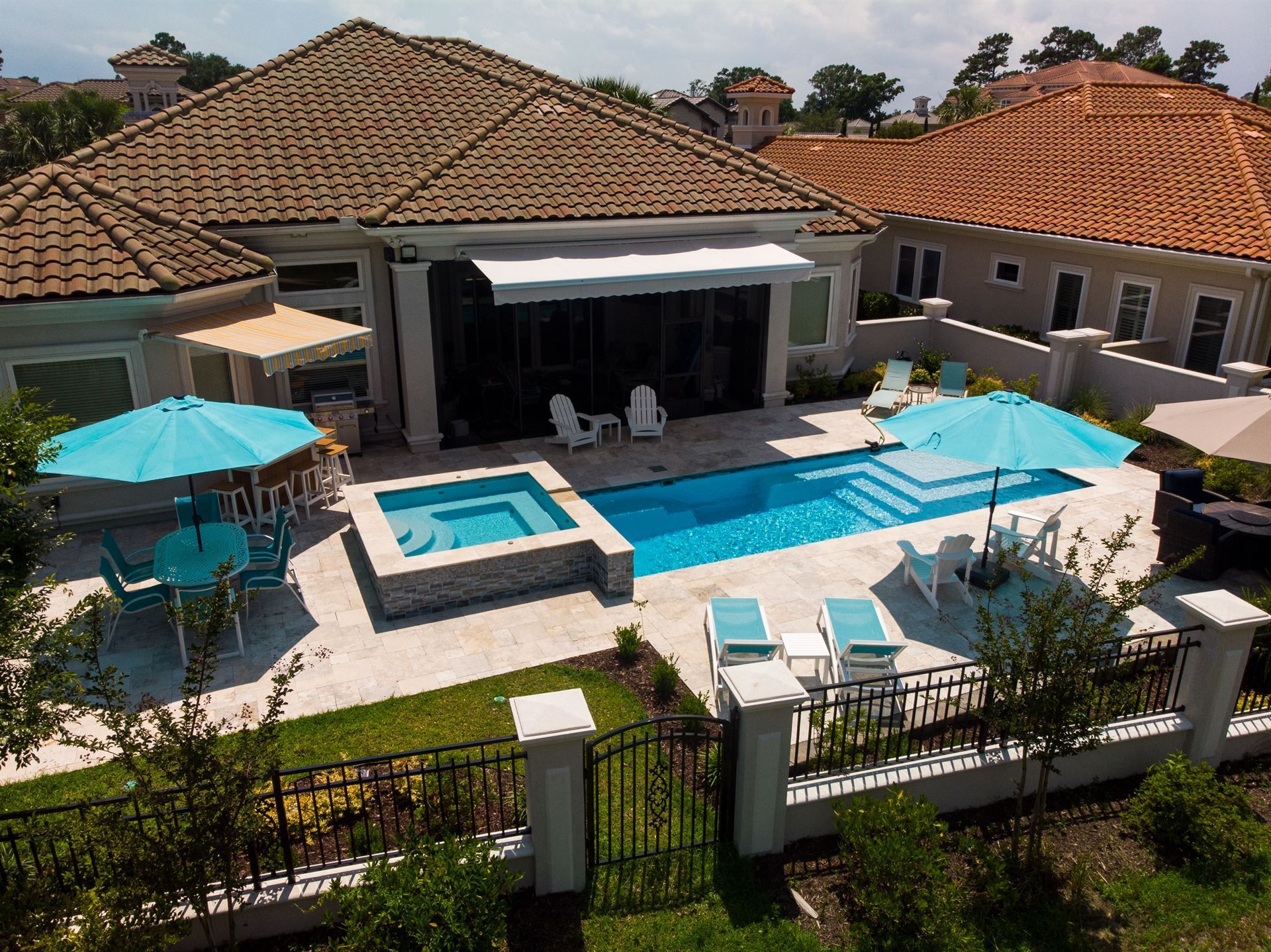 Luxury backyard with pool, patio seating, and a modern house with terracotta roof tiles