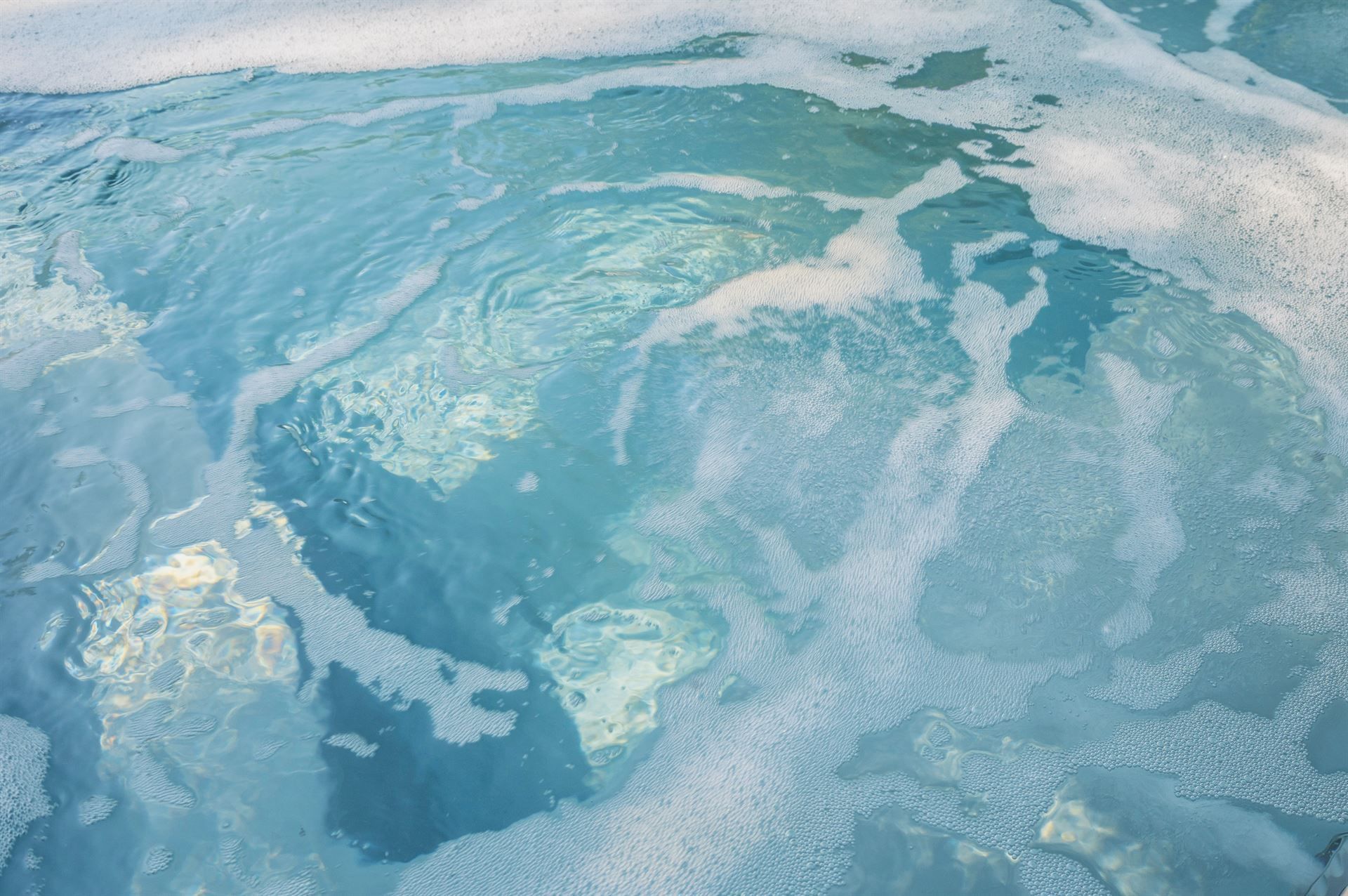 Blue icy water with swirling white foam and a frozen surface