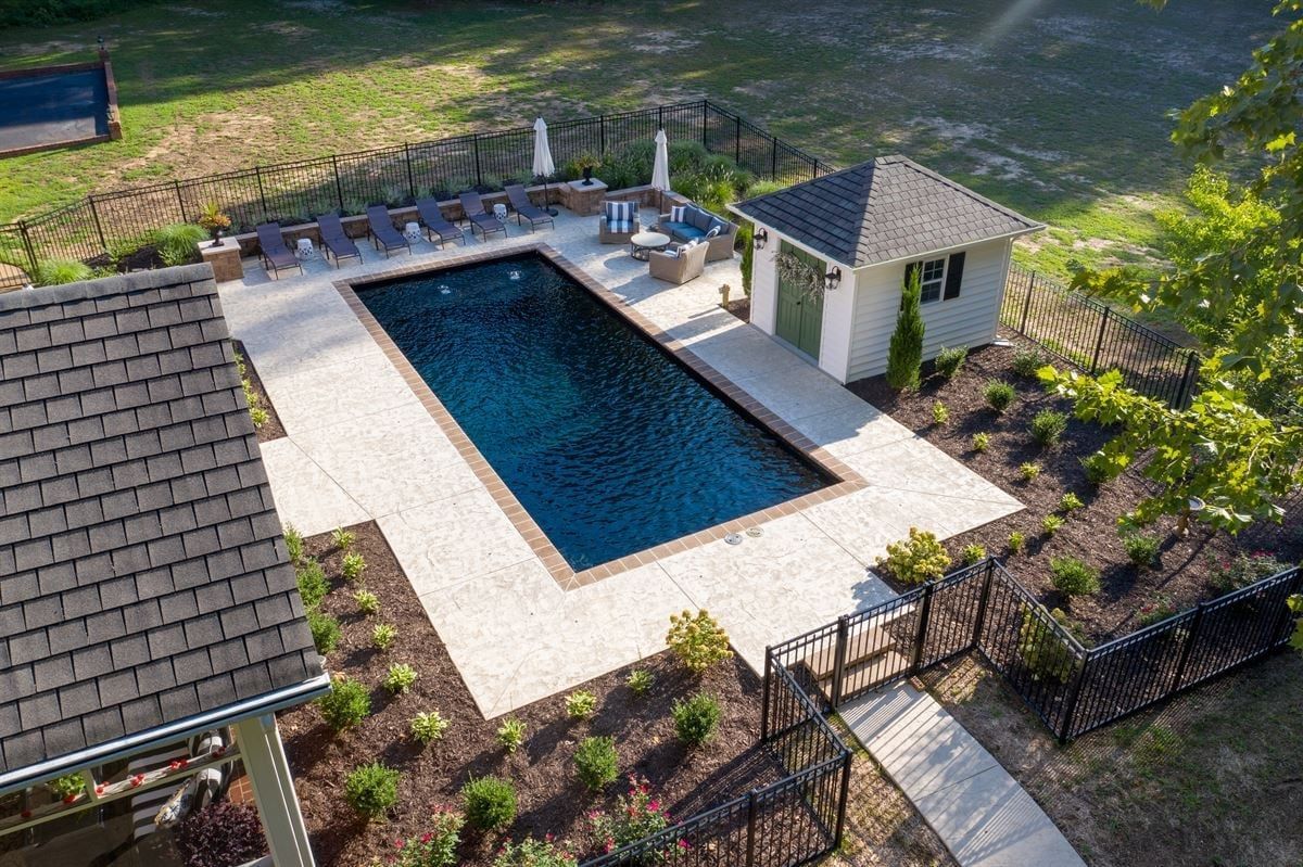 Aerial view of a backyard pool with a white deck, gazebo, and surrounding fence.