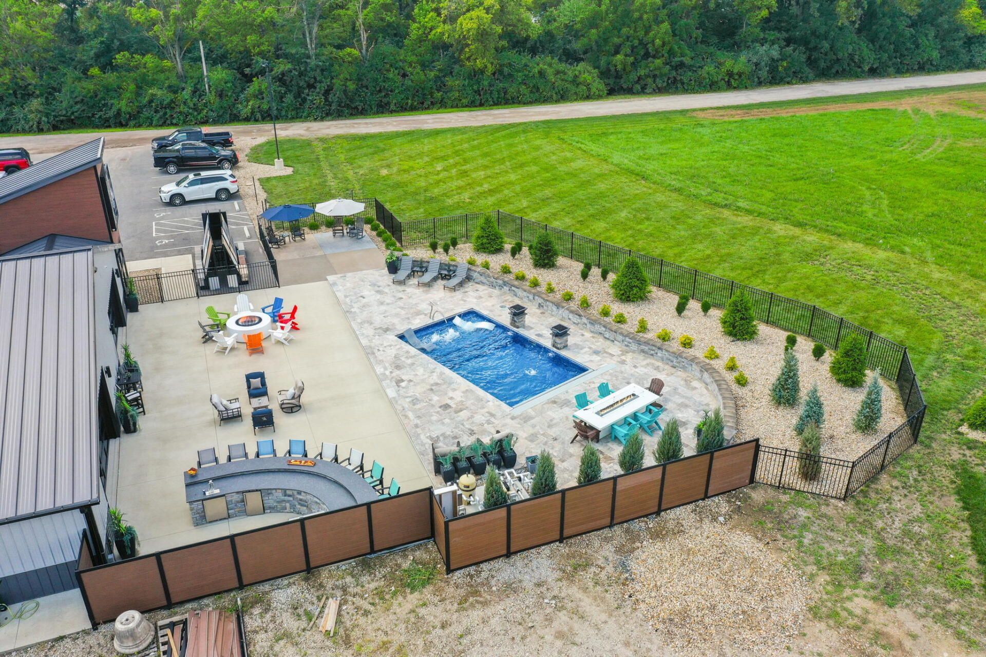 Backyard patio with above-ground pool, lounge chairs, and fenced seating area beside a large green lawn