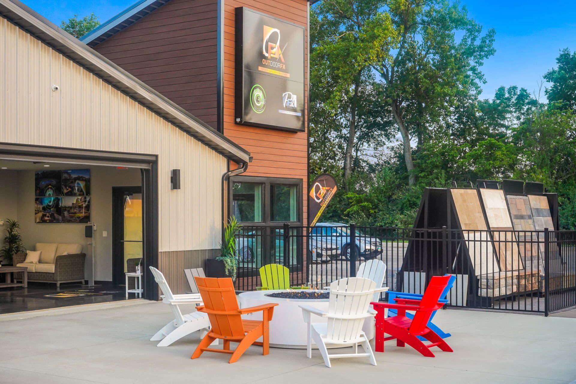 Outdoor patio with colorful chairs beside a building and fenced deck under blue sky
