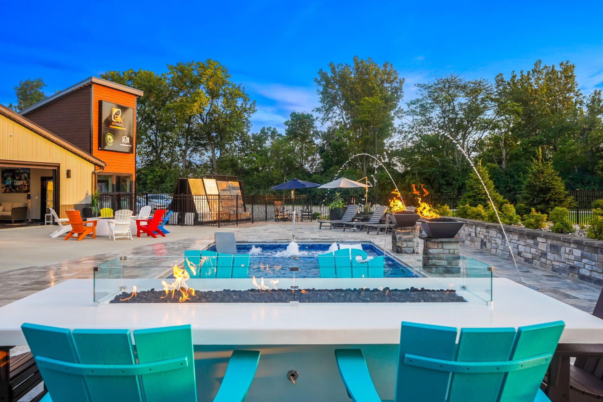 Backyard pool patio with turquoise chairs, fire pit, and a house at sunset