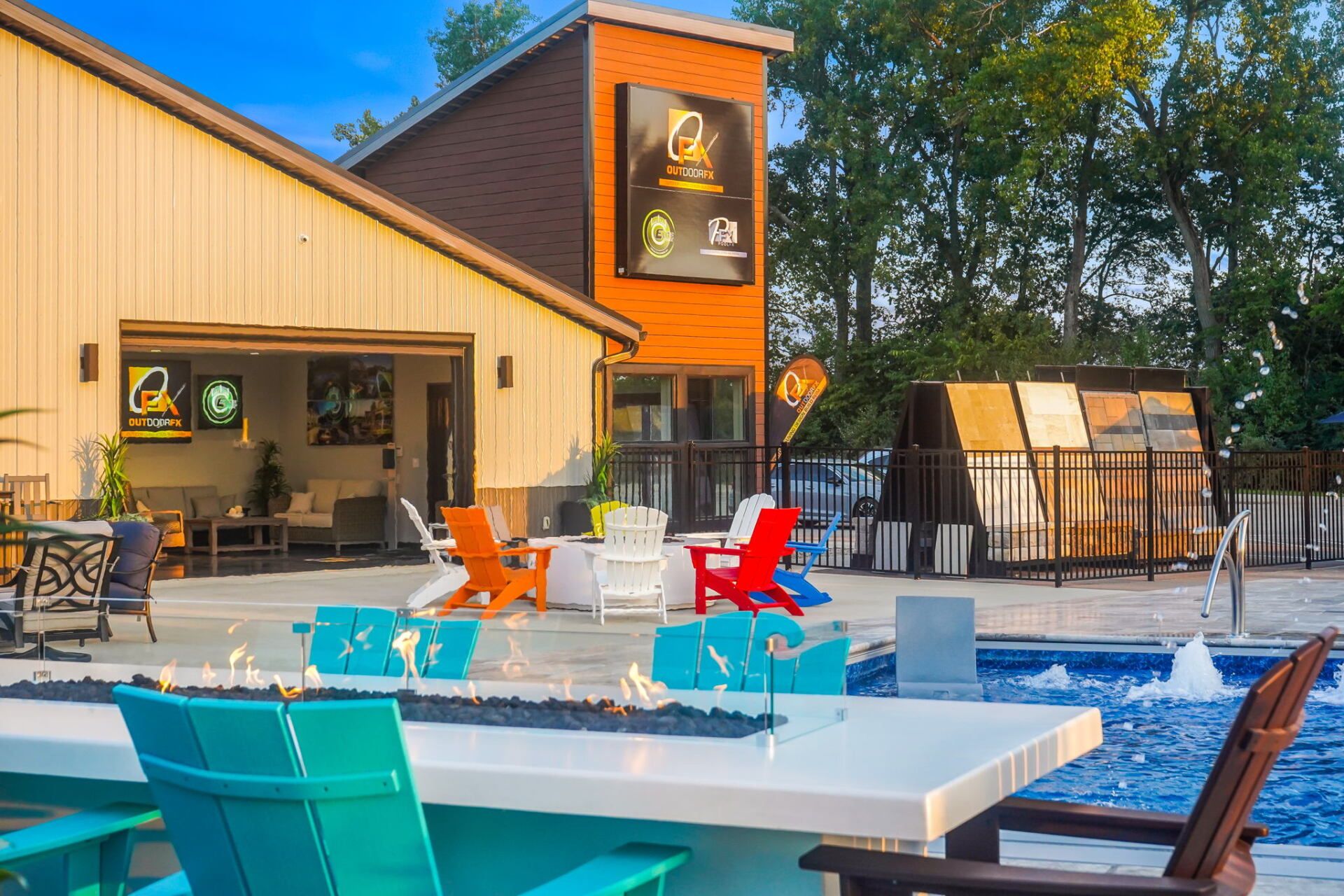 Modern poolside patio with colorful chairs beside a building and pergola at sunset