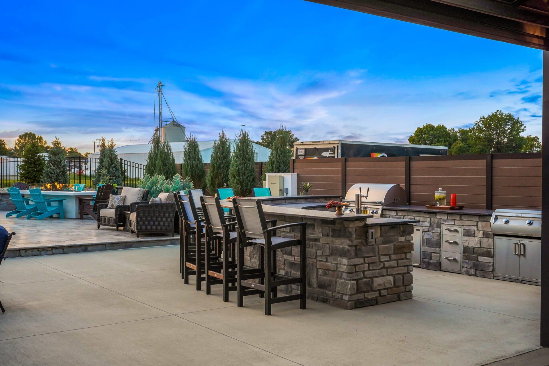 Outdoor patio with stone bar, high chairs, grill, and blue sky at dusk