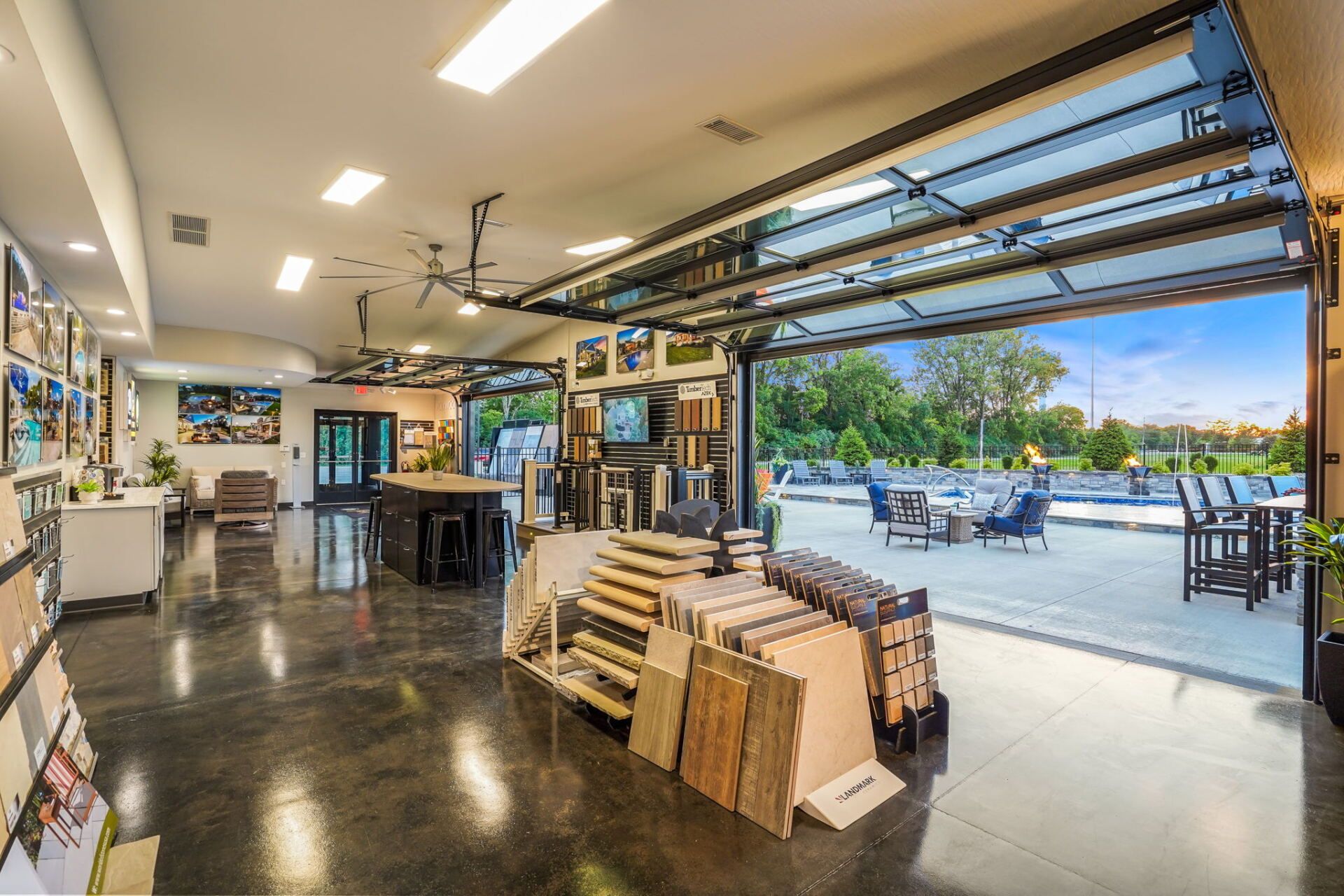 Open garage-style shop interior with stacked materials and work tables, opening to an outdoor patio in daylight