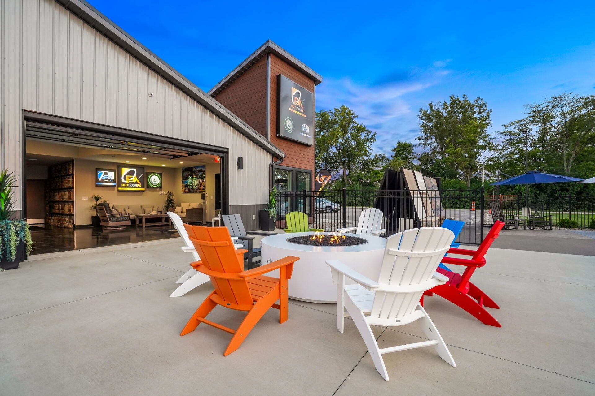 Outdoor patio with white table and colorful chairs beside a building under a blue sky