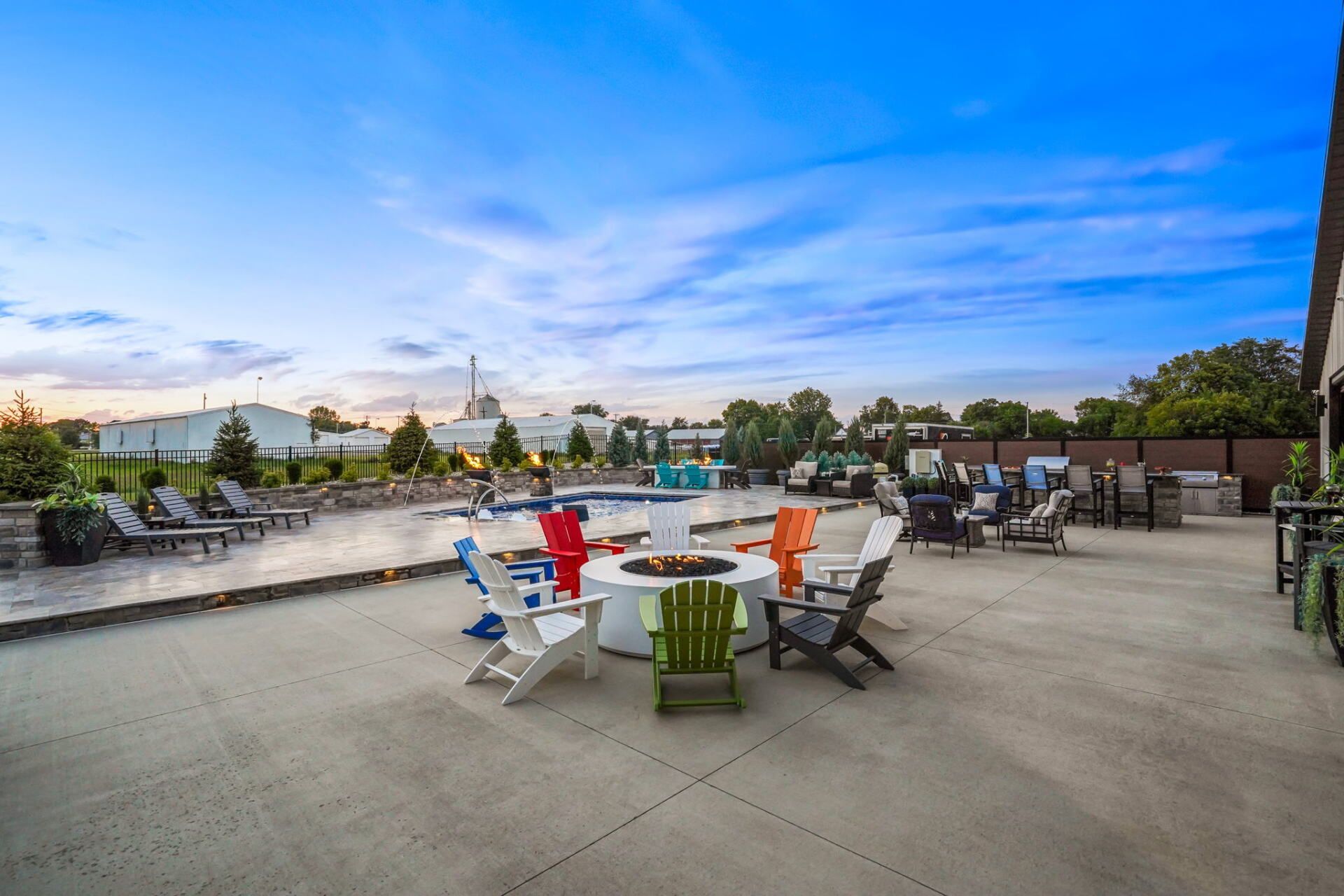 Rooftop pool deck with colorful chairs, lounge seating, and city skyline at sunset