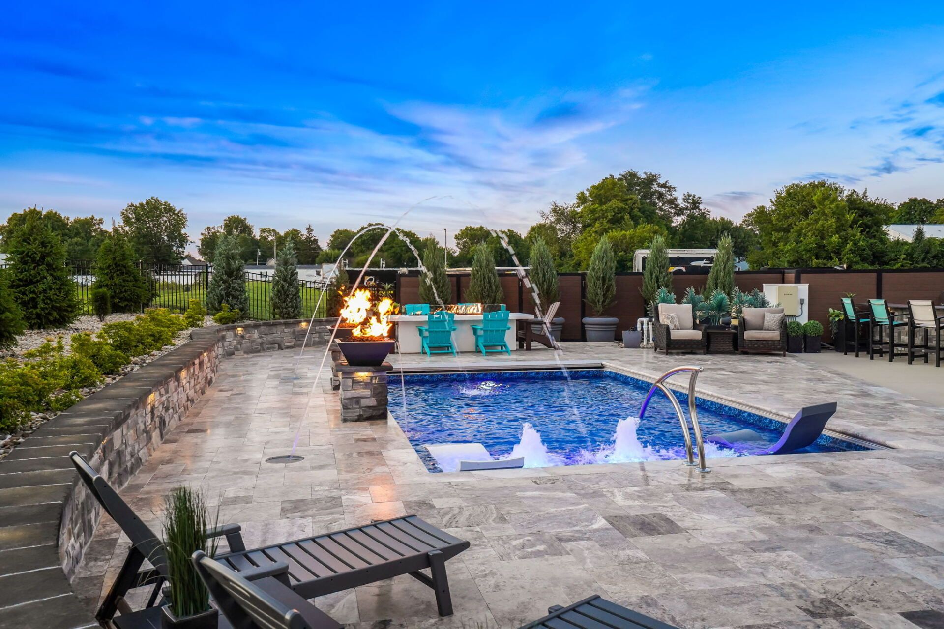 Rooftop pool deck with lounge chairs, fire pit, and blue sky at sunset