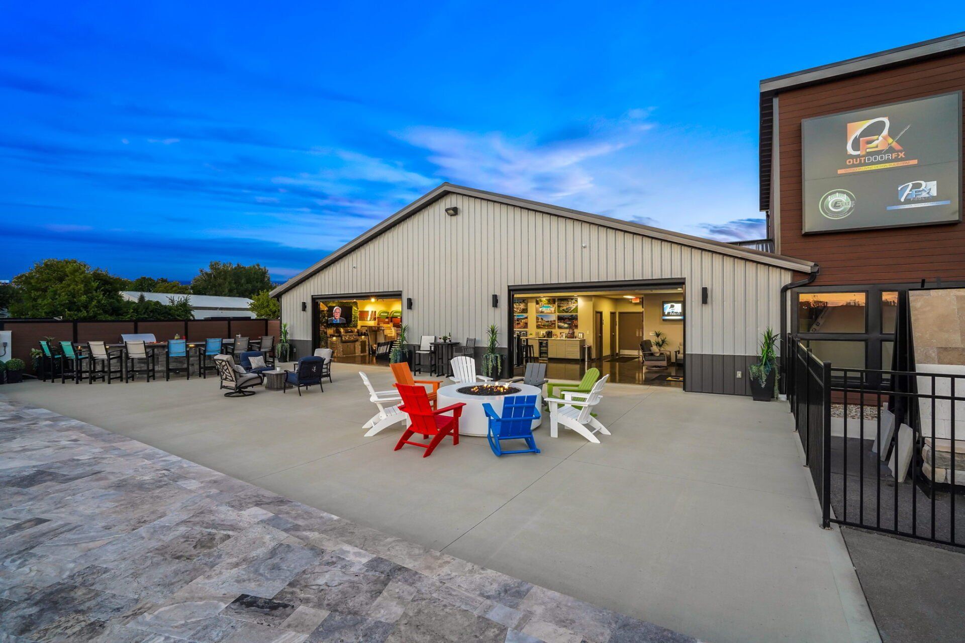 Outdoor café with colorful chairs in front of a lit building at dusk